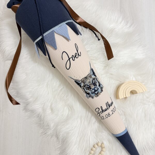 Beige-blaue Stoffschultüte mit gesticktem Luchsmotiv, Namen Joel, Wimpelkette und personalisiertem Einschulungsdatum