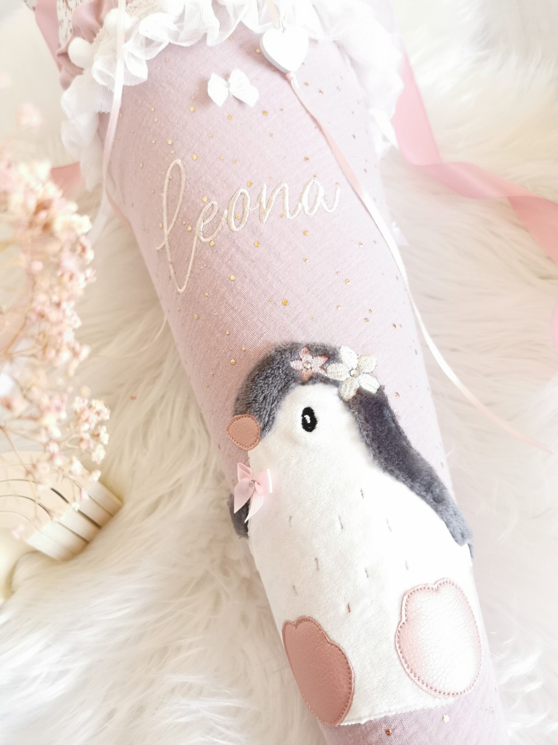 Pinguinmotiv mit Blumenverzierung und Namensstickerei Leona auf rosa Stoff