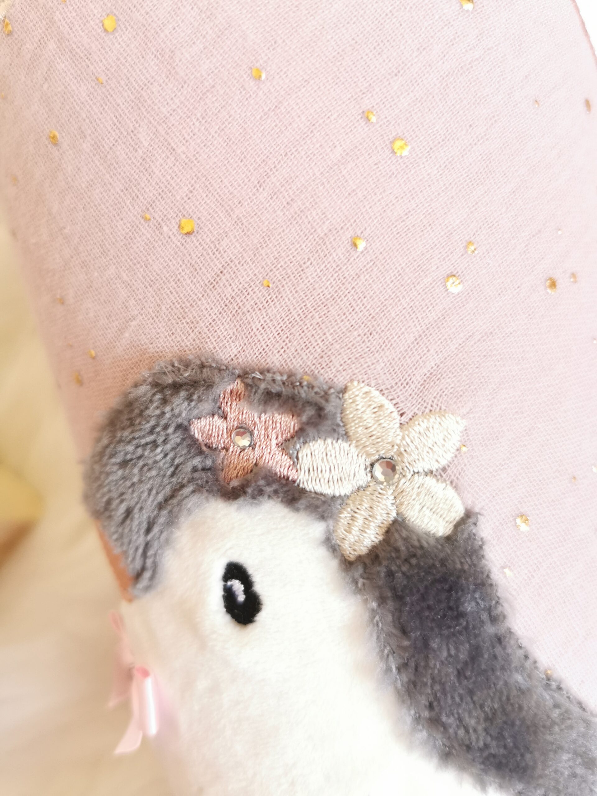 Nahaufnahme des Pinguinkopfes mit weichem grauem Stoff, Blüten und Strasssteinen