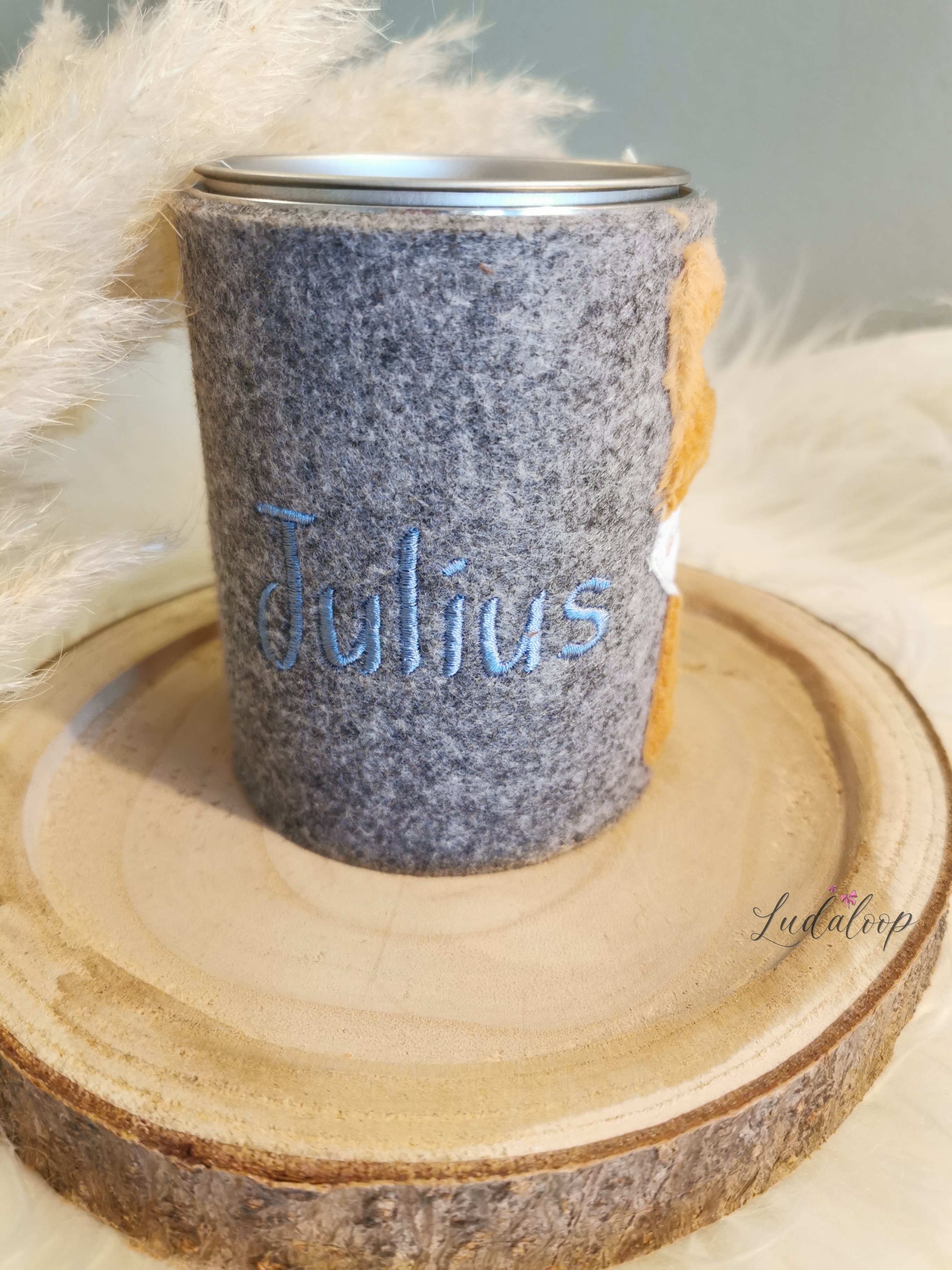 Grauer Filzmantel der Spardose mit dem blau aufgestickten Namen Julius